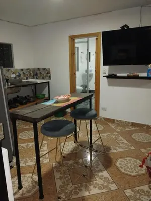 a table and two stools in a living room at Los balconesll in Medellín