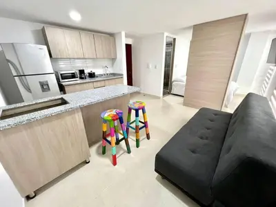 a living room with a black couch and a kitchen at Bonito apartaestudio /manizales in Manizales