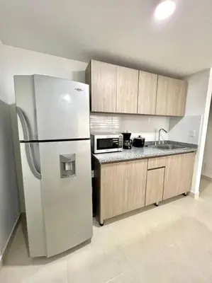 a kitchen with a white refrigerator and wooden cabinets at Bonito apartaestudio /manizales in Manizales
