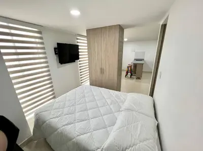 a bedroom with a white bed and a television at Bonito apartaestudio /manizales in Manizales