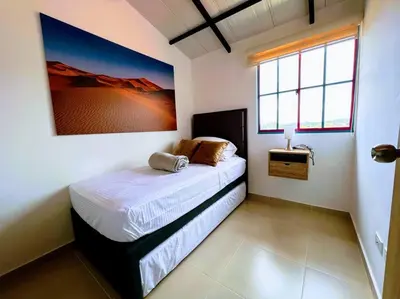 a bedroom with a bed with a picture on the wall at Apto Nuevo, Tranquilo, Bonito, 5 min Plaza Principal in Guatapé