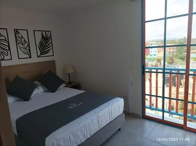 a bedroom with a bed and a view of a balcony at Apto Nuevo, Tranquilo,Bonito,5 min Plaza Principal in Guatapé