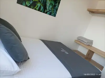 a white bed with a black and white comforter at Apto Nuevo, Tranquilo,Bonito,5 min Plaza Principal in Guatapé