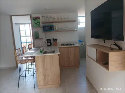 a kitchen with a counter and a television on a wall at Apto Nuevo, Tranquilo,Bonito,5 min Plaza Principal in Guatapé