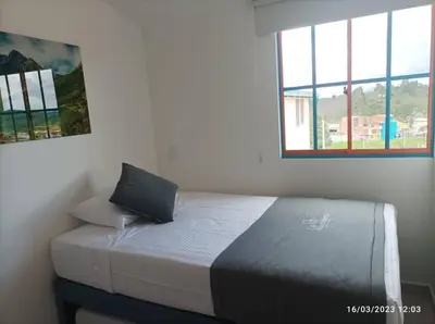 a bed sitting in a room with a window at Apto Nuevo, Tranquilo, Bonito, 5 min Plaza Principal in Guatapé
