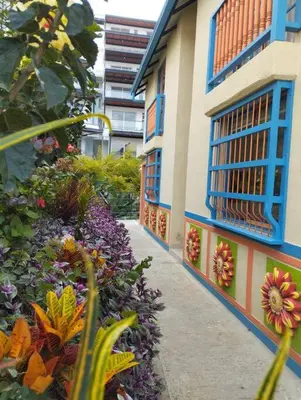 a building with colorful flowers next to a sidewalk at Apto Nuevo, Tranquilo, Bonito, 5 min Plaza Principal in Guatapé