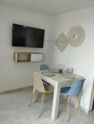 a white table with chairs and a tv on a wall at Apto Nuevo, Tranquilo, Bonito, 5 min Plaza Principal in Guatapé