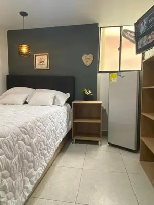a bedroom with a white bed and a refrigerator at HABITACIÓN independiente con COCINA EN LAURELES ESTADIO para 3 personas in Medellín