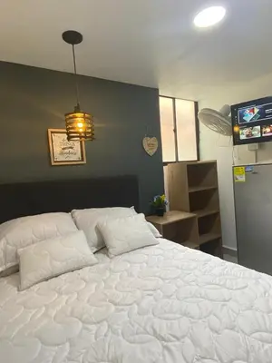 a large white bed in a room with a television at HABITACIÓN independiente con COCINA EN LAURELES ESTADIO para 3 personas in Medellín