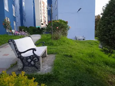 a bench sitting in the grass next to a building at Lindo y acogedor apto cerca Mall Hospitales U Autónoma in Manizales
