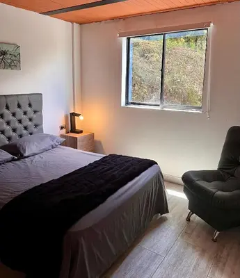 a bedroom with a bed and a window and a chair at Cabaña el mirador azul in Guatapé