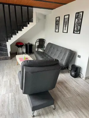 a leather couch in a living room with a staircase at Cabaña el mirador azul in Guatapé