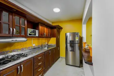 a kitchen with wooden cabinets and a stainless steel refrigerator at La Posada de Sebastian in Medellín