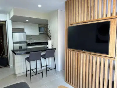 a kitchen with a bar with stools and a television on a wall at Exclusivo Loft en el poblado-rodeado de naturaleza 501 in Medellín