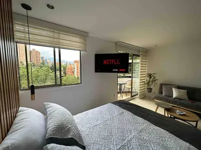 a bedroom with a bed and a tv on the wall at Nature and calm in El Poblado 505 in Medellín