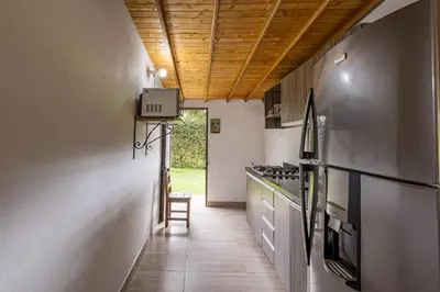 a hallway of a kitchen with a table and a chair at Buho Cabaña Santa Elena in Santa Elena