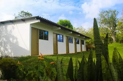 a small white building in a yard with trees at Hotel Casa de Teja in Norcasia