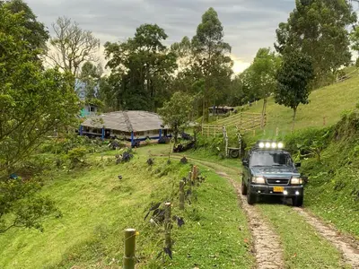 a truck driving down a dirt road in a field at Hostal las Hamacas in Villamaría