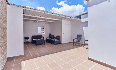 a patio with black chairs and a white wall at 5STARHOMES - Hermosa casa con terraza en Laureles in Medellín