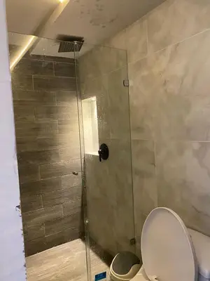 a shower with a glass door next to a toilet at Sage house de 2 alcoba la 70 laurles estadio in Medellín