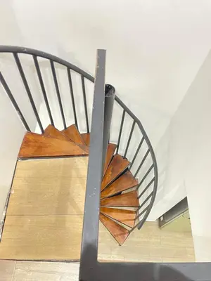 a spiral staircase with a metal railing in a room at Sage house de 2 alcoba la 70 laurles estadio in Medellín