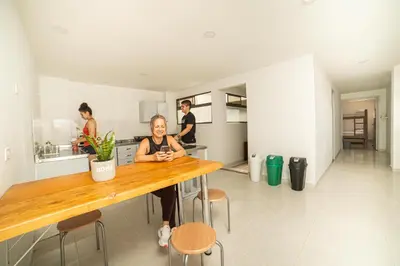 a woman sitting at a table in a kitchen at Tu Refugio Acogedor en el corazón de Medellín Hab Privada A in Medellín