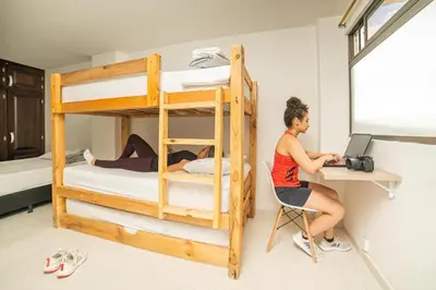 a woman sitting at a desk in a room with bunk beds at Alojamiento en el corazón de Medellín Hab Privada B in Medellín